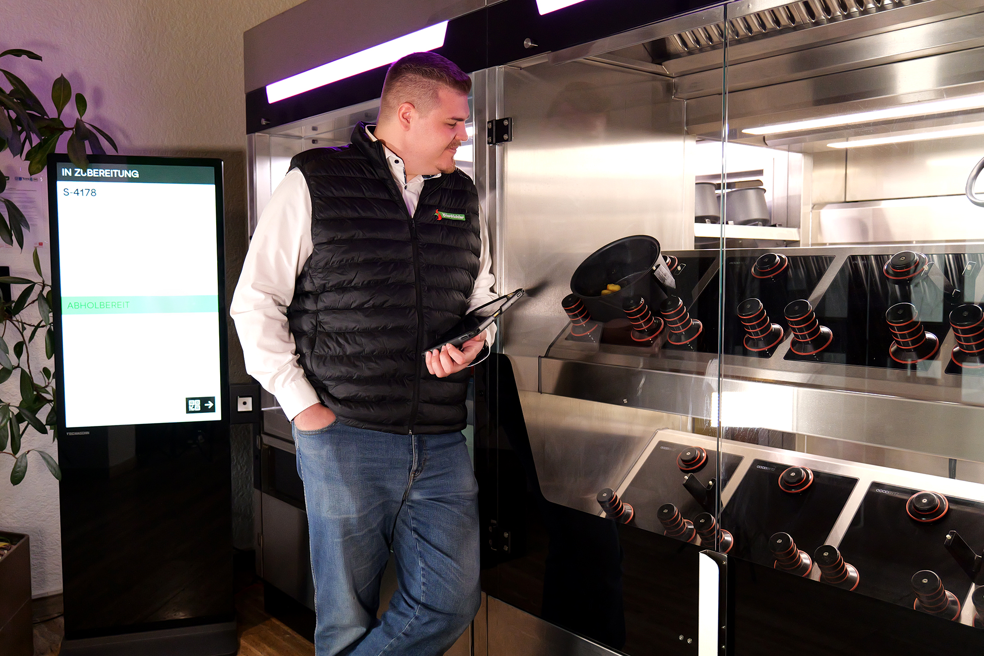 Genussmomente im Alltag mit dem Kochroboter von Bierbichler Ein Mann steht neben einer Glasvitrine.