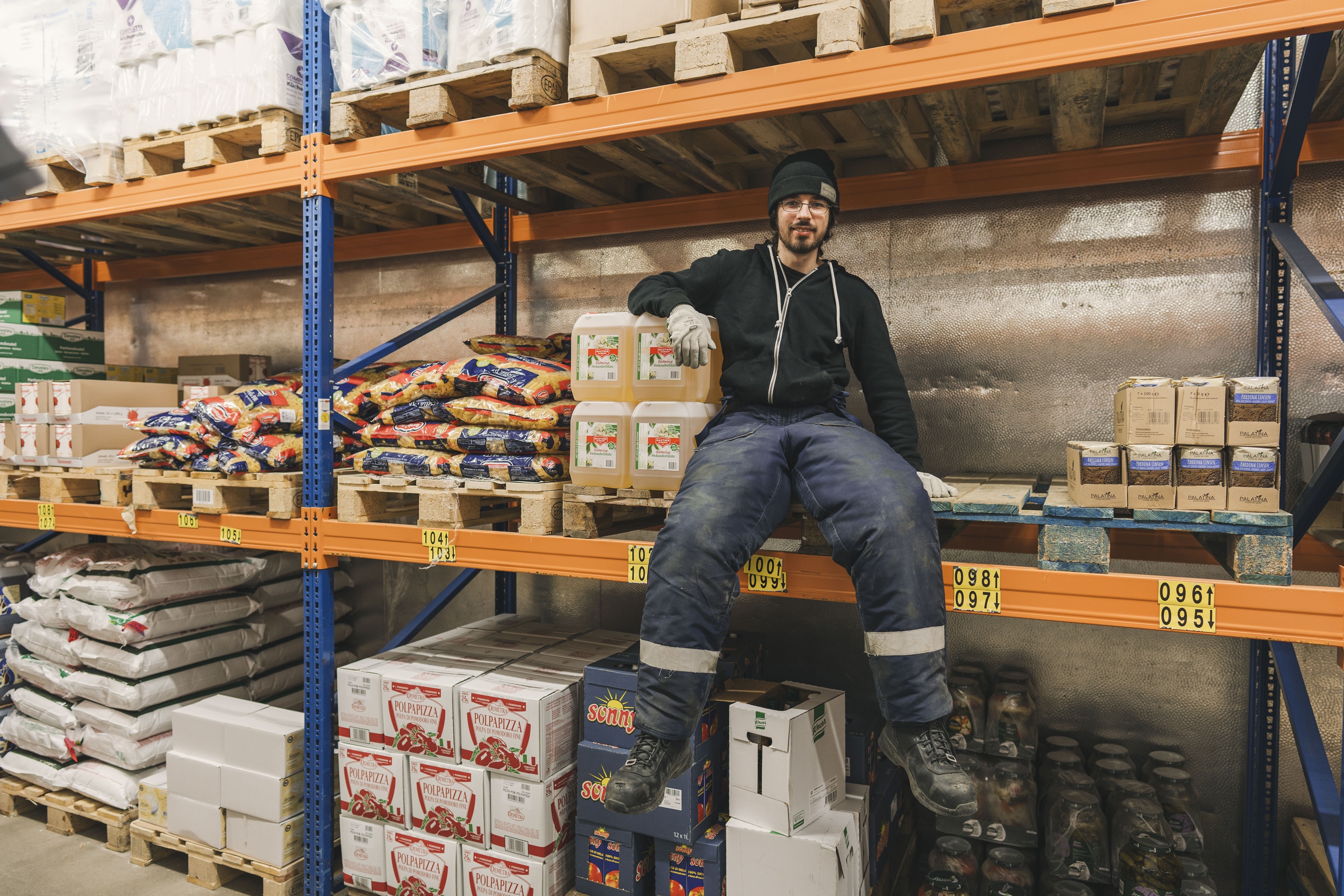 mehr für die Azubis tun... Ein Mann sitzt auf einem Regal in einem Lagerhaus.