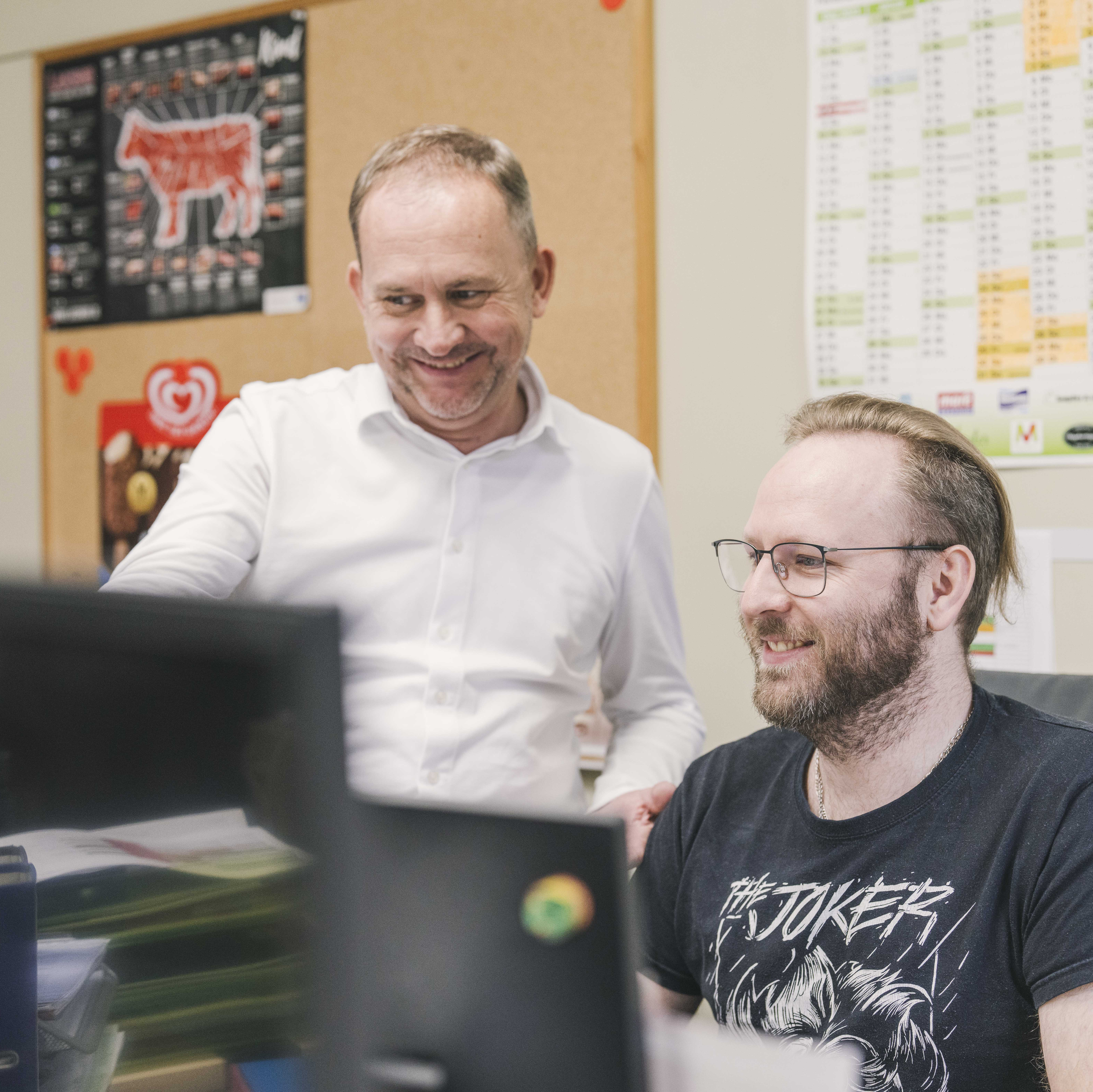 Wir sind für Sie da! Eine Fachberaterin sitzt am Telefon vor Ihrem PC und unterhält sich mit viel Freude mit Ihrem Kunden